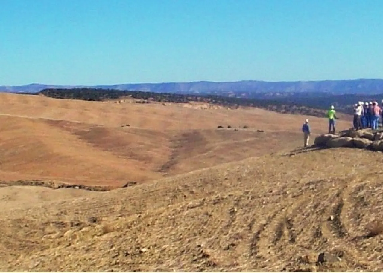 A person standing on top of a sandy hill.